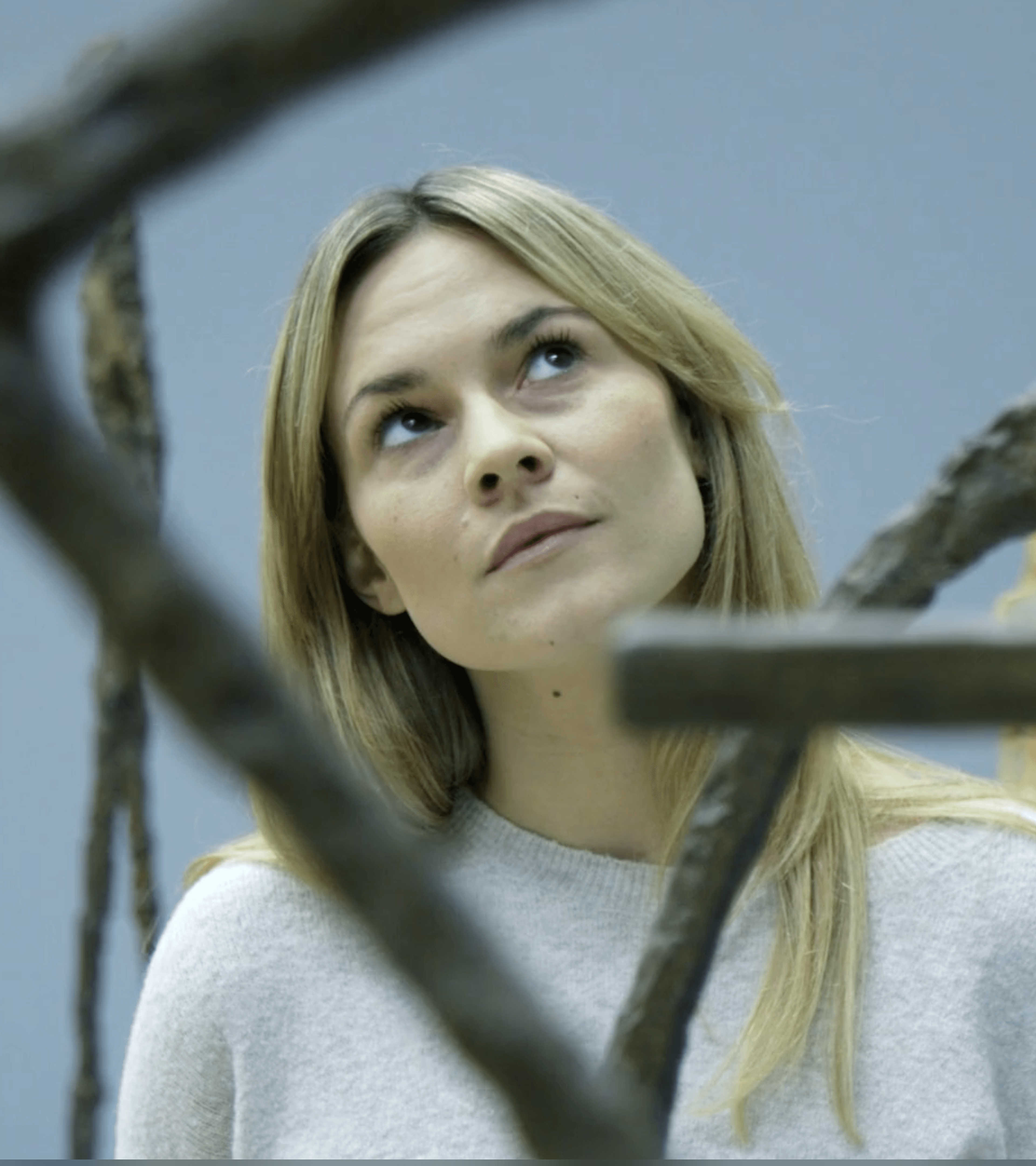 Eine Frau betrachtet ein Kunstwerk aus Metall.