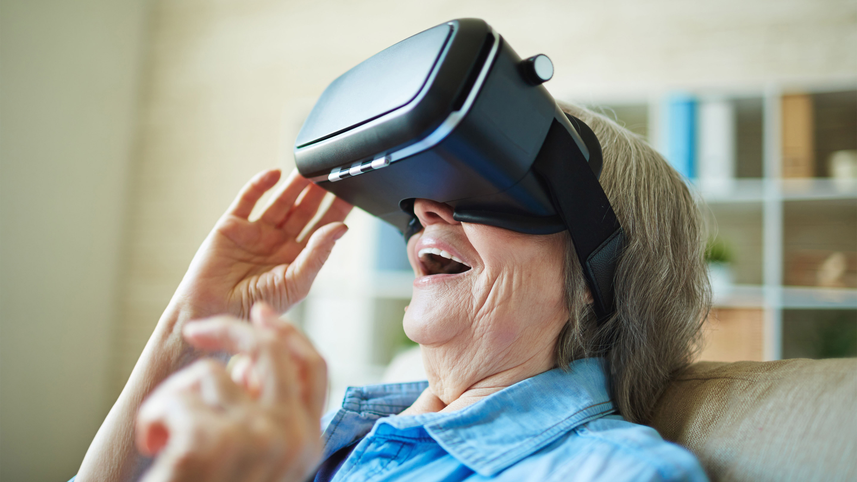 Eine Seniorin benutzt erstaunt eine futuristisch aussehende VR-Brille der Universität Zürich.